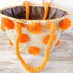 bolso cesta de doum con pompones anaranjados