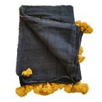 Manta negra con pompones color mostaza